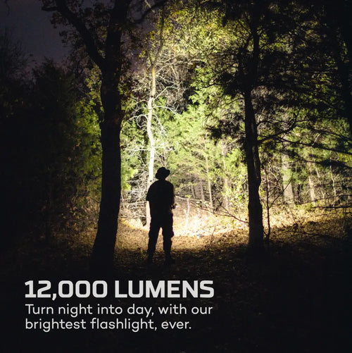 A powerful bright white 12K flashlight illuminating a forest path at night for outdoor use