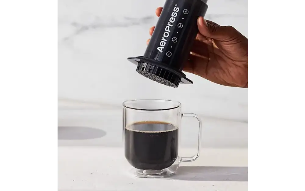Musta Aerobie AeroPress kahvinvalmistuslaite, jossa on teksturoitu uritettu pohja ja valkoinen brändäys