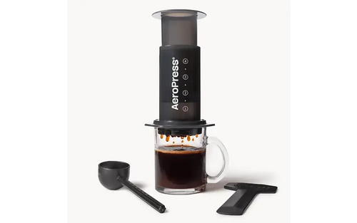 Black aeropress kahvinvalmistuslaite läpinäkyvällä mäntällä ja mittamerkinnöillä varustetulla lasimukilla