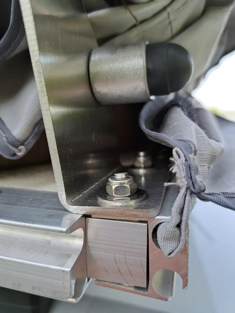 Stainless steel hinge with black rubber cap and hex nut securing metal frame on the back side of auton kattoteltta ilma pitkä 1.4 harmaa
