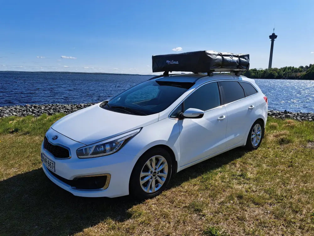 Valkoinen kia ceed farmariauto mustalla kattolaatikolla auton kattoteltta ilma pitkä 1.6 harmaa takakuvassa