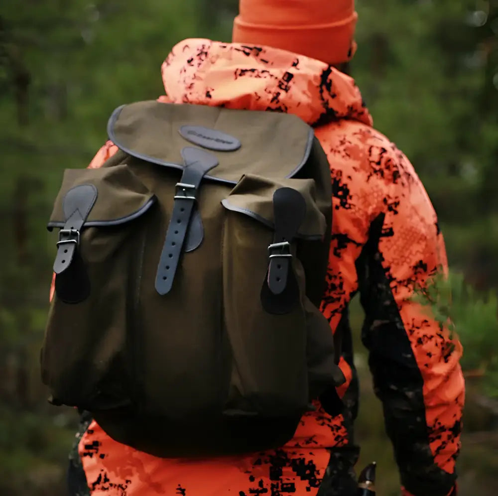 Olive green canvas backpack bear claw jätkän reppu with black leather straps and buckles visible from the back side