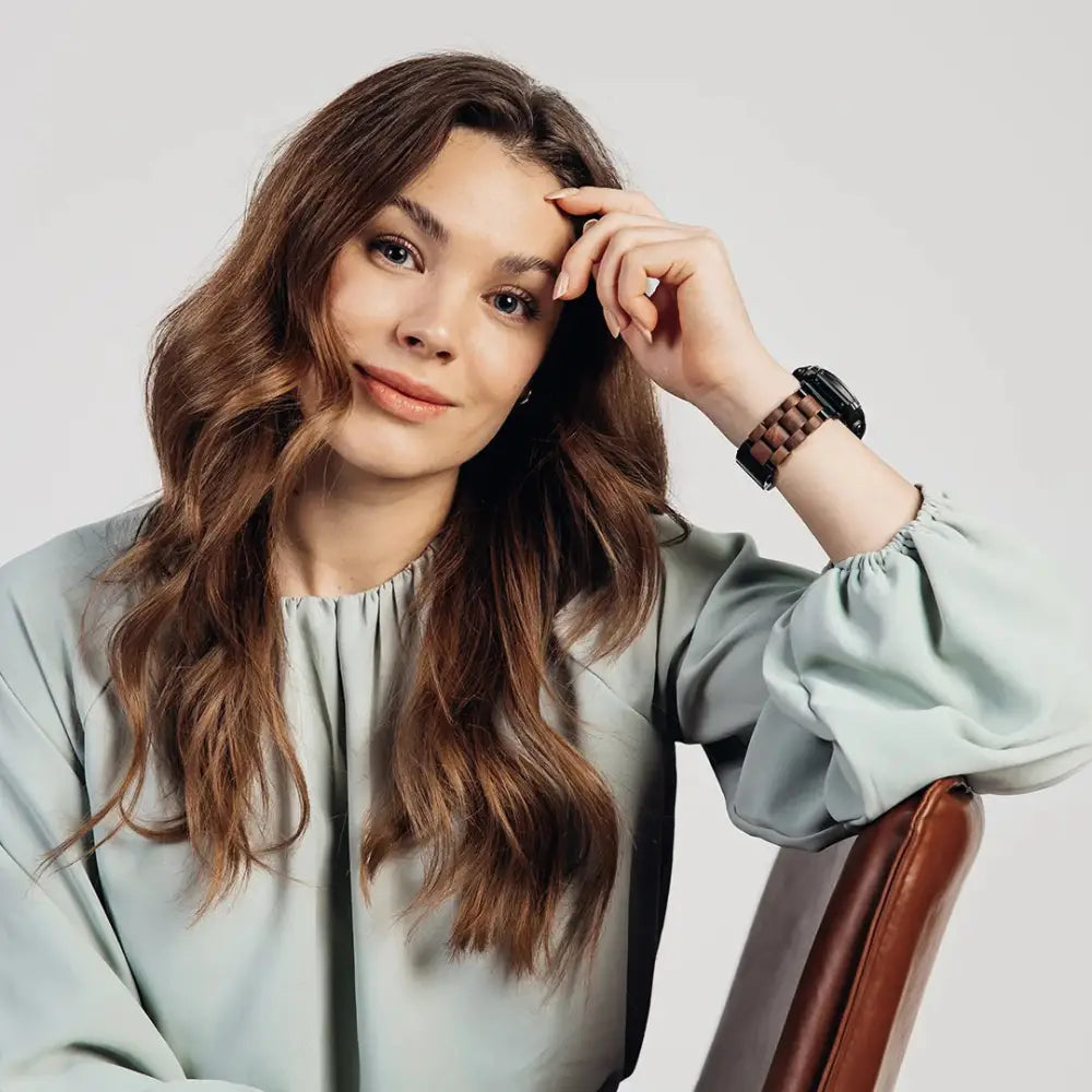 A sleek black smartwatch with a wooden textured garmin quickfit pähkinäpuu band on the wrist