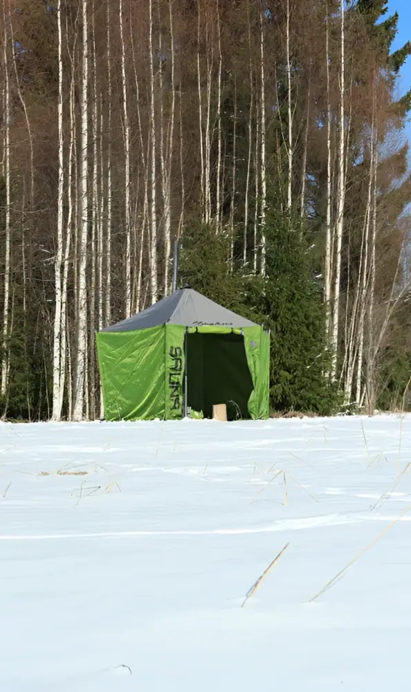 Vihreä ja harmaa ski-doo-brändätty pop-up telttasauna lumisella kentällä koivumetsän keskellä