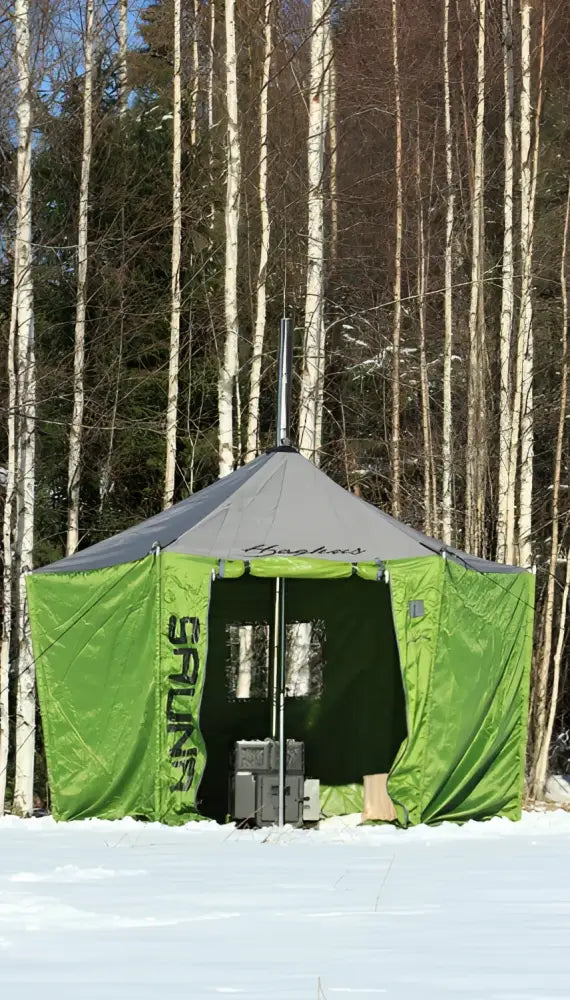 Haghus telttasauna on vihreä ja harmaa kannettava saunateltta, jossa on sauna-logo, pystytetty lumiseen metsään