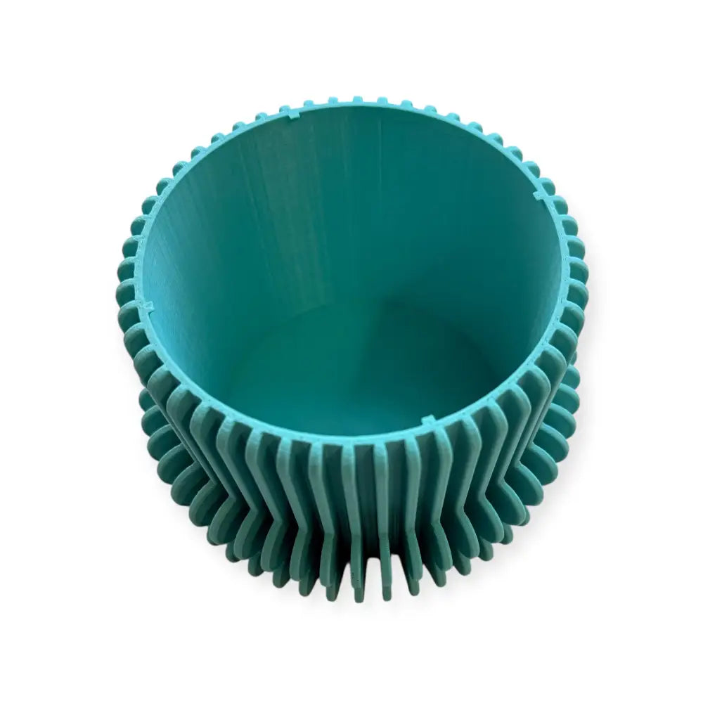 Tealvärinen muovinen kukkaruukun suojus pyöreällä uurteisella ulkopinnalla ja sileällä sisäpinnalla