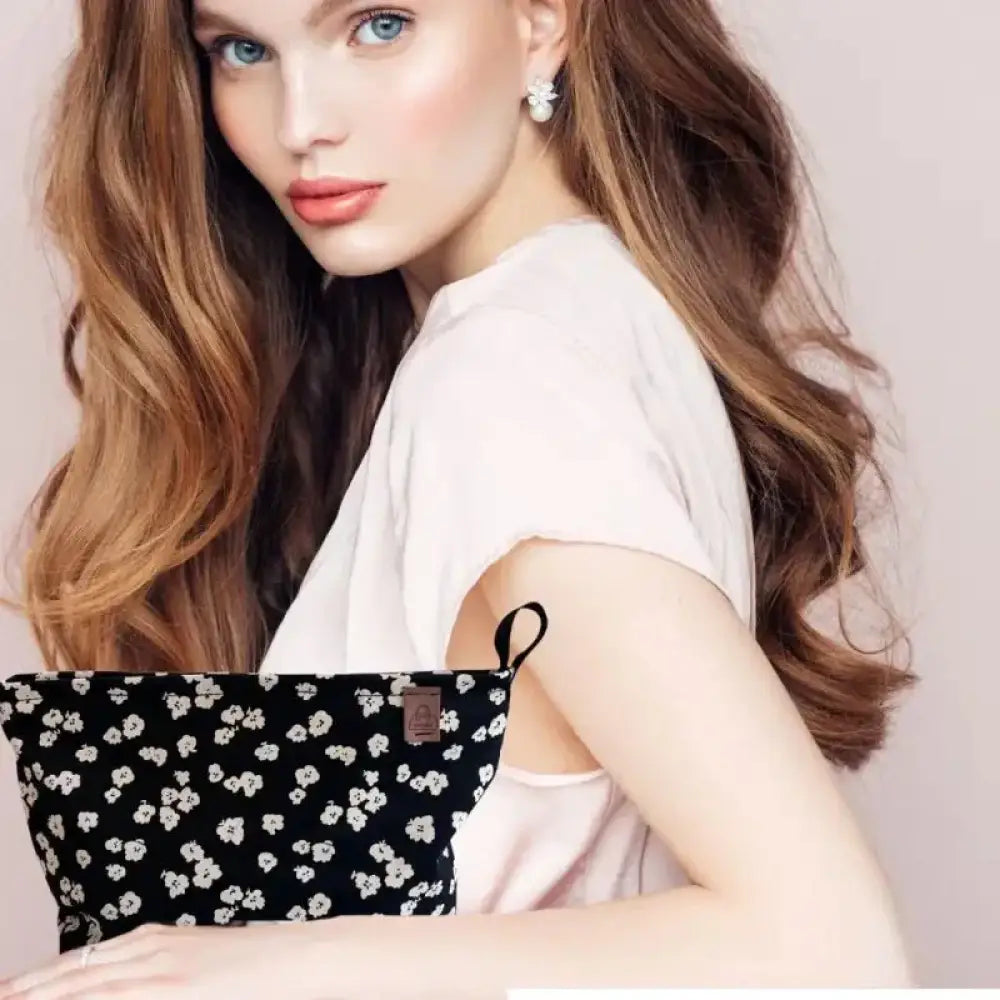 Meikkilaukku kia black fabric pouch with white floral pattern and brown leather tag