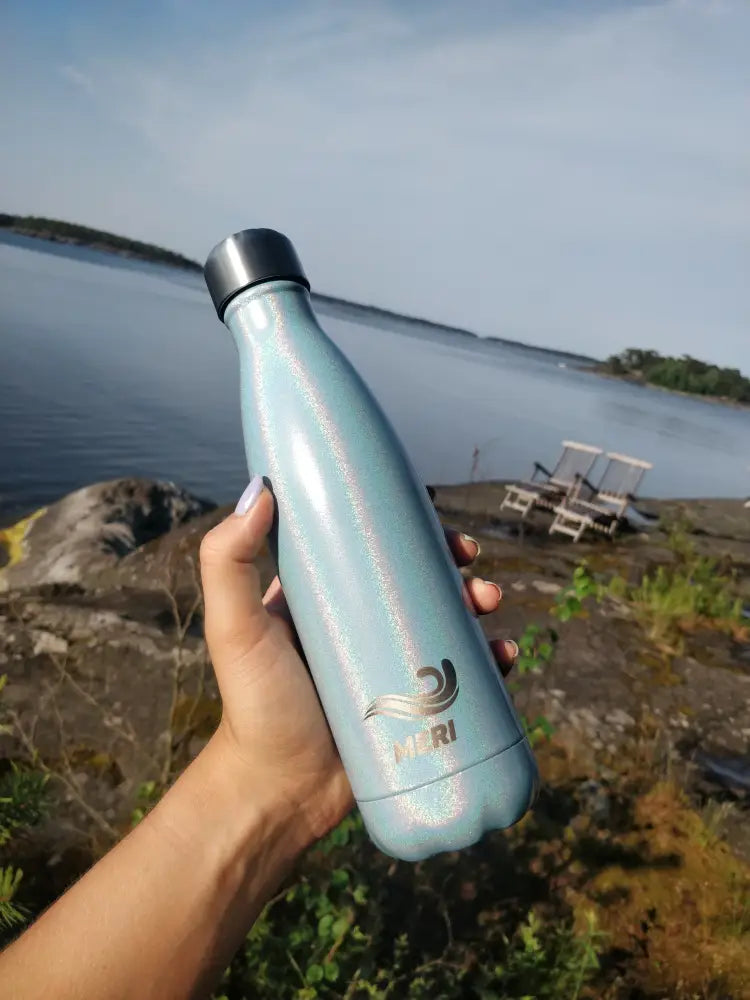 A sleek iridescent light blue Meribottles MERMAID 500 ml stainless steel water bottle with silver cap and wave logo