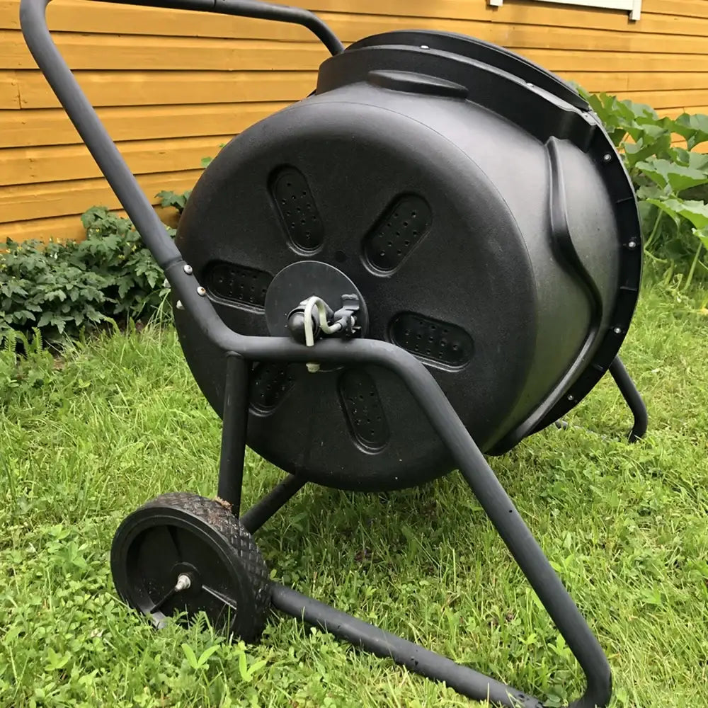 Musta muovinen pikkuvihreä rumpukompostori metallikehyksellä ja pyörillä helppoon siirtoon ulkotiloissa