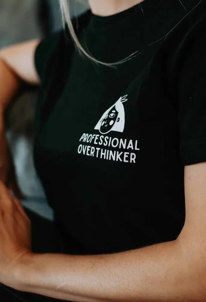 Musta lyhythihainen t-paita valkoisella tyylitellyllä kasvojen grafiikalla ja tekstillä professional overthinker