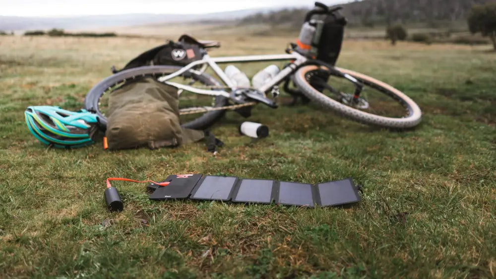 Musta taitettava pwr solarpanel 10 watt aurinkopaneeli oranssilla latauskaapelilla nurmikolla