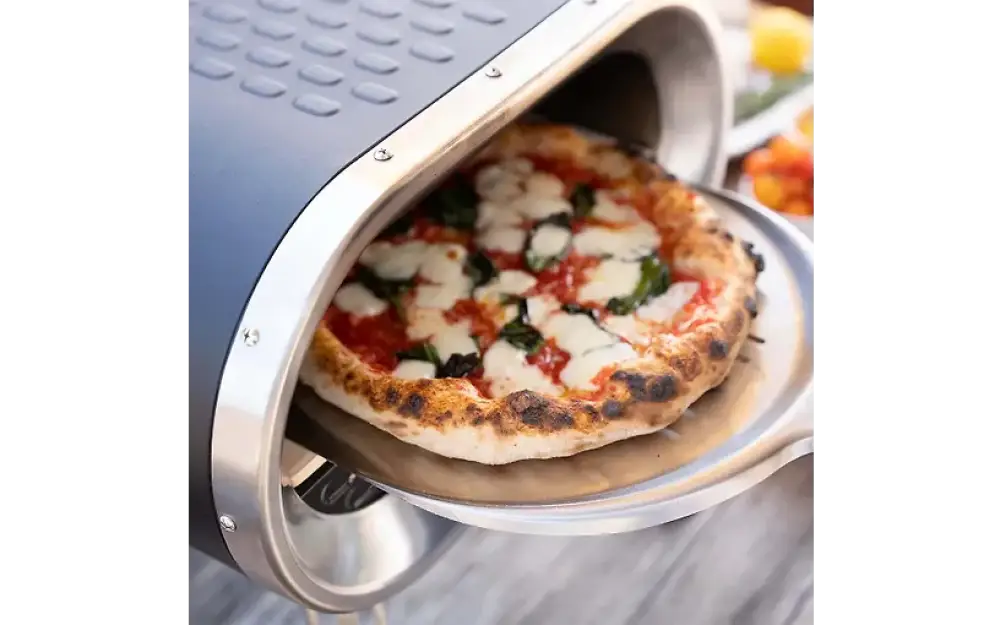 Revolve kaasukäyttöinen pizzauuni paistaa kullanruskean margherita-pizzan vihreillä basilikanlehdillä
