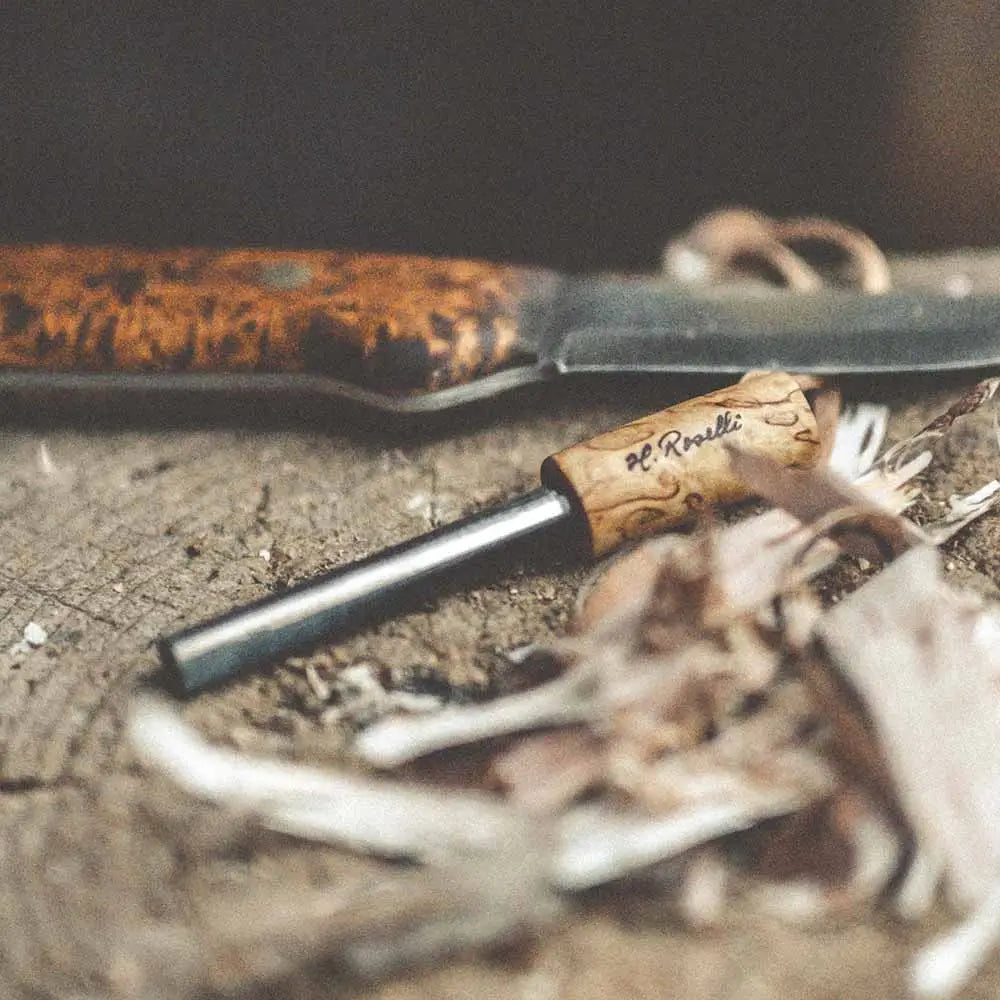 A sleek black Roselli Firesteel fire starter with a natural wood handle engraved with h
