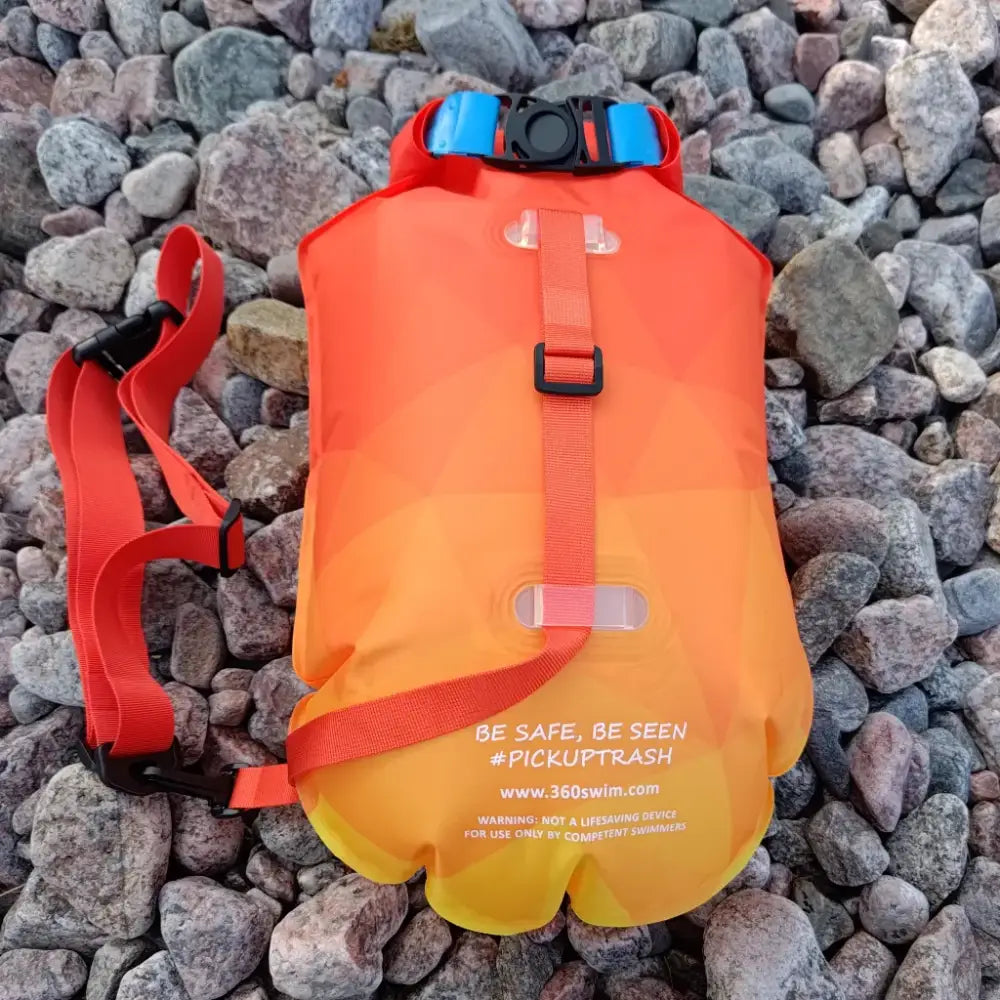 Kirkkain oranssi ultra dazzle drybag buoy ilmatäytteinen uimuri punaisilla remmeillä ja sinisellä soljella turvallisuuteen vedenpäällä